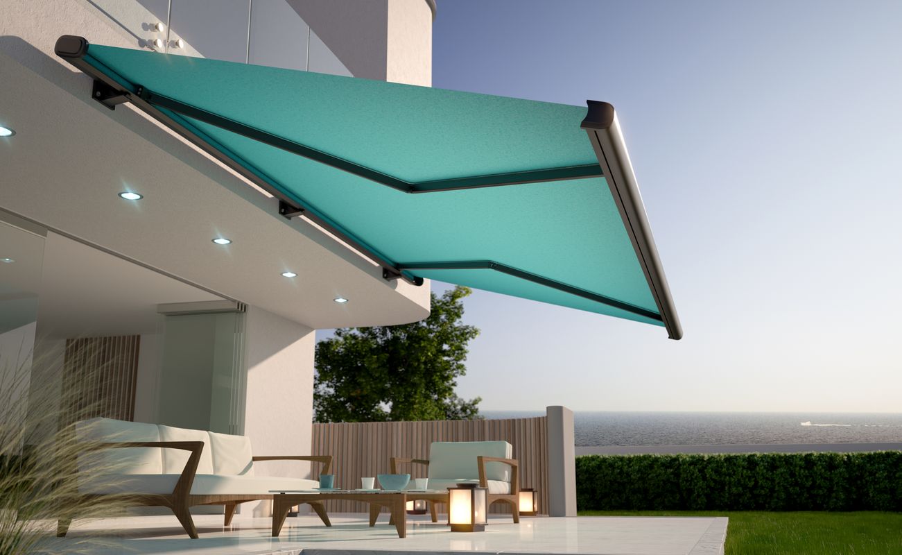 Terrasse mit einem modernen, ausfahrbaren Sonnenschutz in Türkis, Möbeln und Blick auf das Meer im Hintergrund.